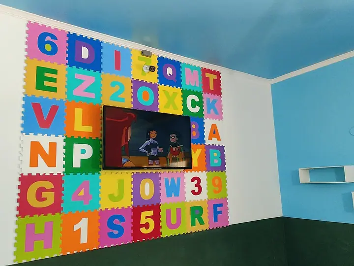 Parede de letras coloridas e televisão na brinquedoteca