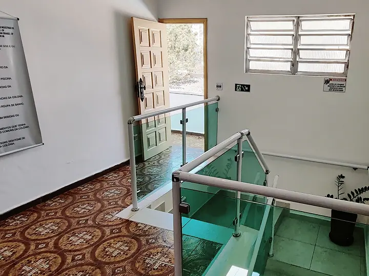 Escada com corrimão de vidro e quadro de avisos