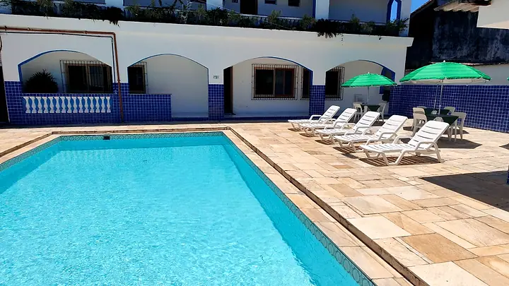 Piscina adulto com espreguiçadeiras brancas e guarda-sóis verdes