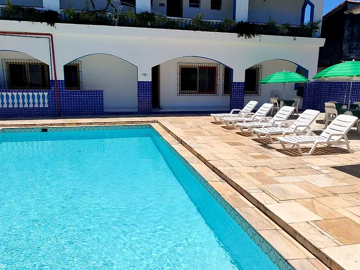 Piscina adulto com fileira de espreguiçadeiras e guarda-sóis