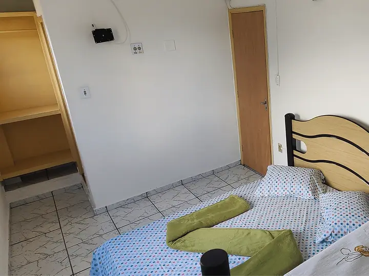 Cama arrumada com toalhas ao lado do armário embutido