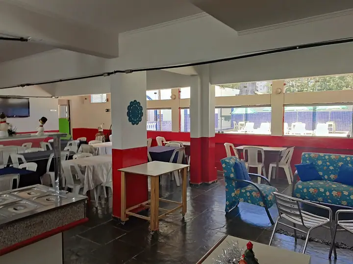 Restaurante com buffet ao centro e mesas com toalhas