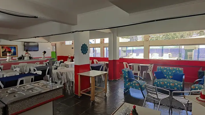 Restaurante com buffet ao centro e mesas com toalhas